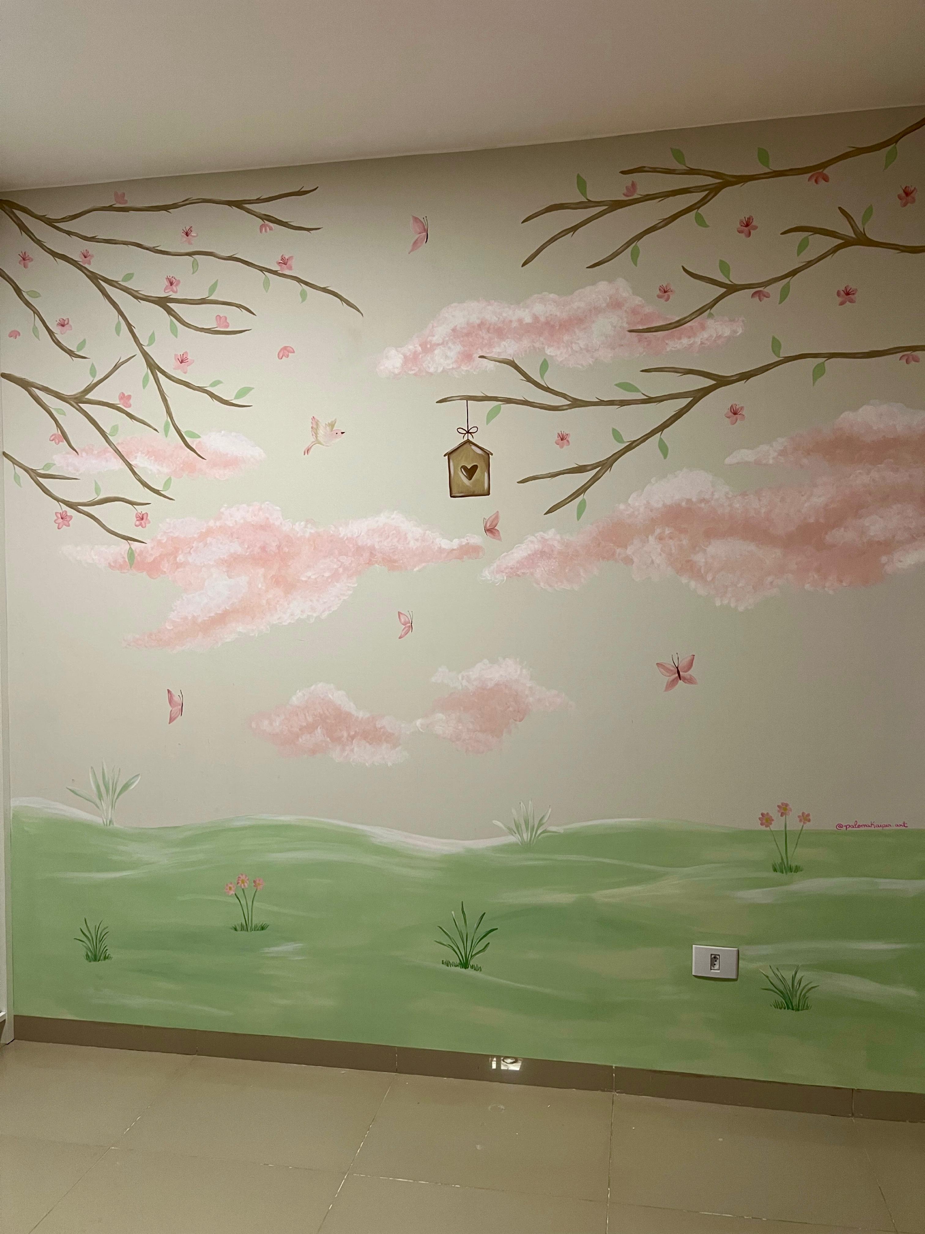 Full view of the mural featuring a green field, pink clouds, flowering branches and birds